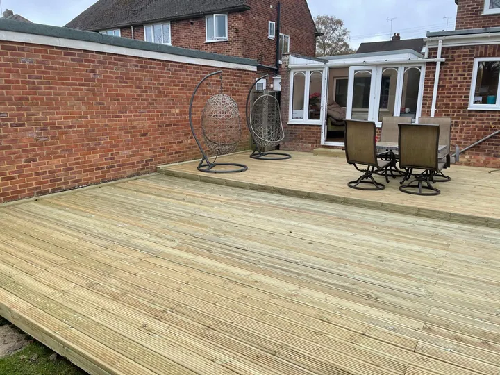 Large timber deck with rattan hanging chairs and a dining set in a brick-walled courtyard garden