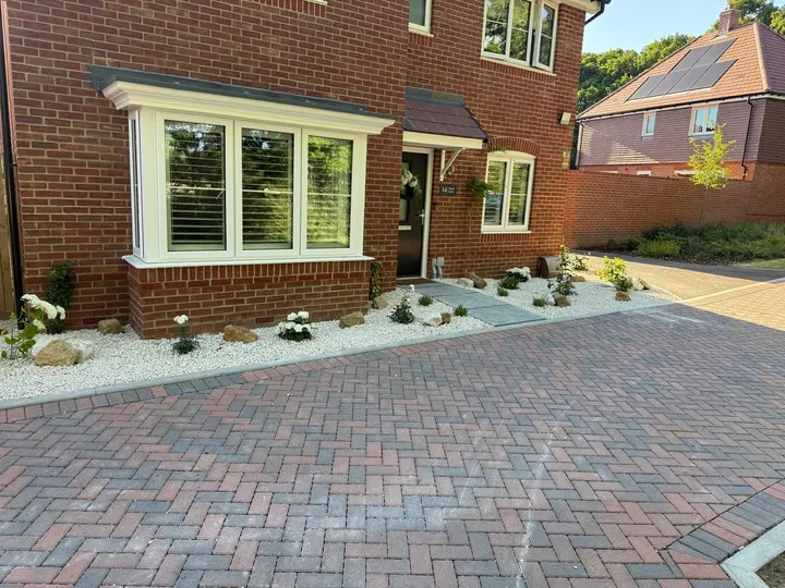 Brindle block-paved driveway with white gravel and planted border alongside a new-build home