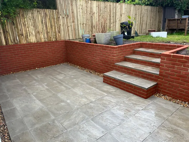 Indian sandstone patio enclosed by red brick retaining walls with sandstone-capped steps