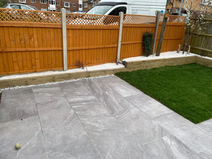 Grey porcelain patio and lawn enclosed by a newly erected close-board fence