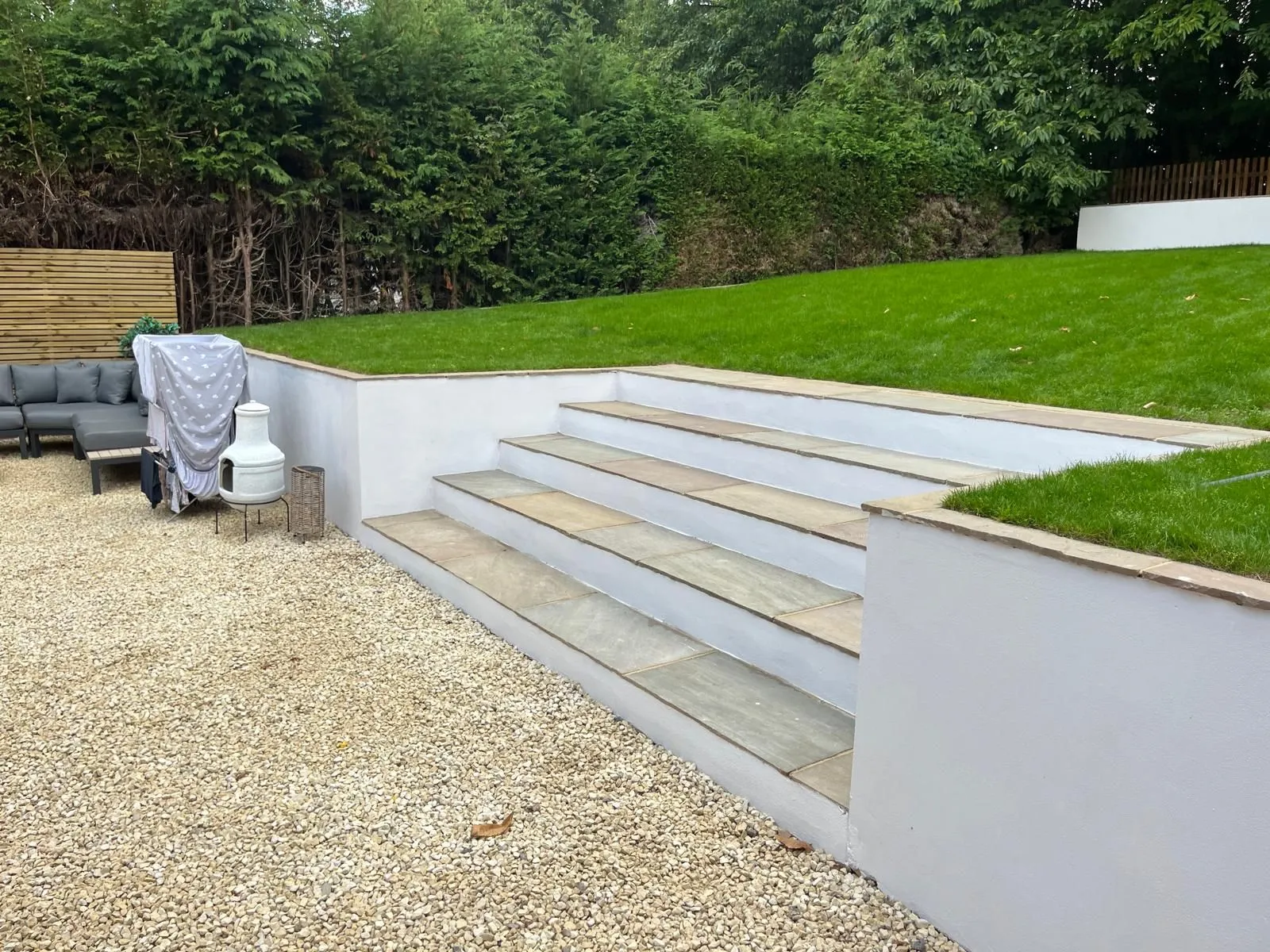 Sandstone steps rising from gravel courtyard up to a perfectly laid new lawn