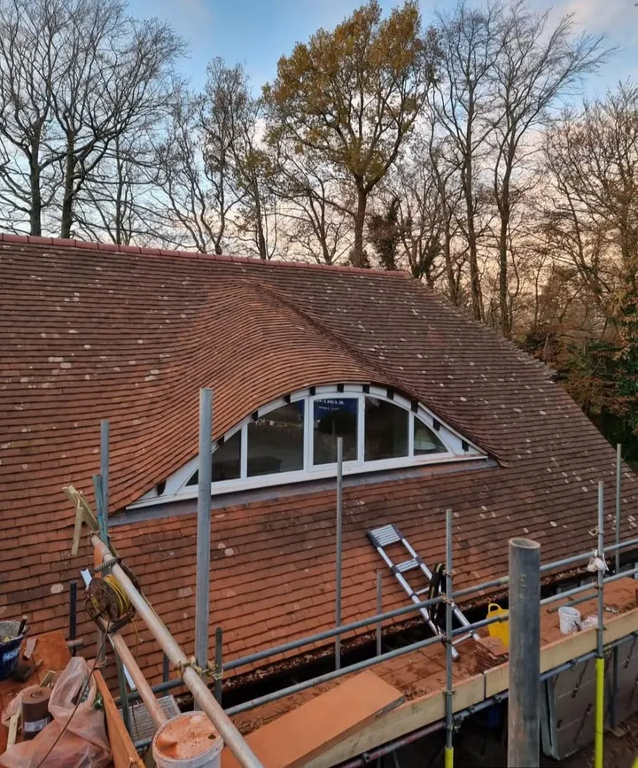Re-roofed property in red clay tiles with curved eyebrow dormer window
