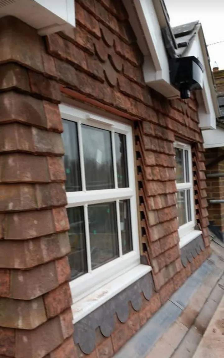 Decorative red plain-tile cladding around window with scalloped courses